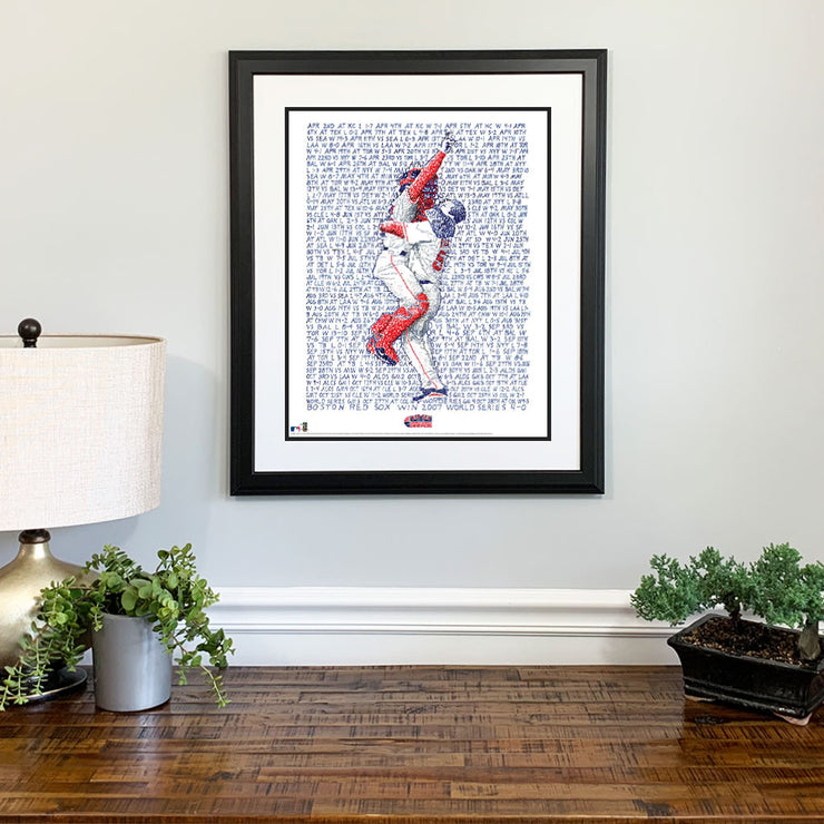 Matted and framed handwritten wall word art celebrating the Red Sox who won the World Series in 2007 hangs over wood table.