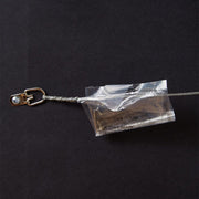 Wire hanger with plastic bag containing nail and hook screwed to back of framed piece of Abraham Lincoln art.