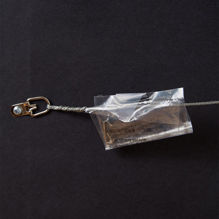 Wire hanger with plastic bag containing nail and hook screwed to back of framed print of handwritten Liberty Bell art.