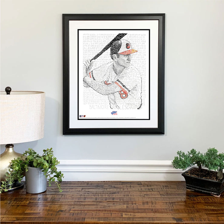 Matted and framed word art print of Baltimore Oriole Cal Ripken at bat in 1983 World Series hangs on wall over wood table.