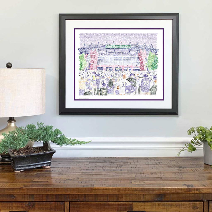 Purple, red, green illustration of front-facing Ravens M&T Stadium and crowd made of words on wall above wood desk.