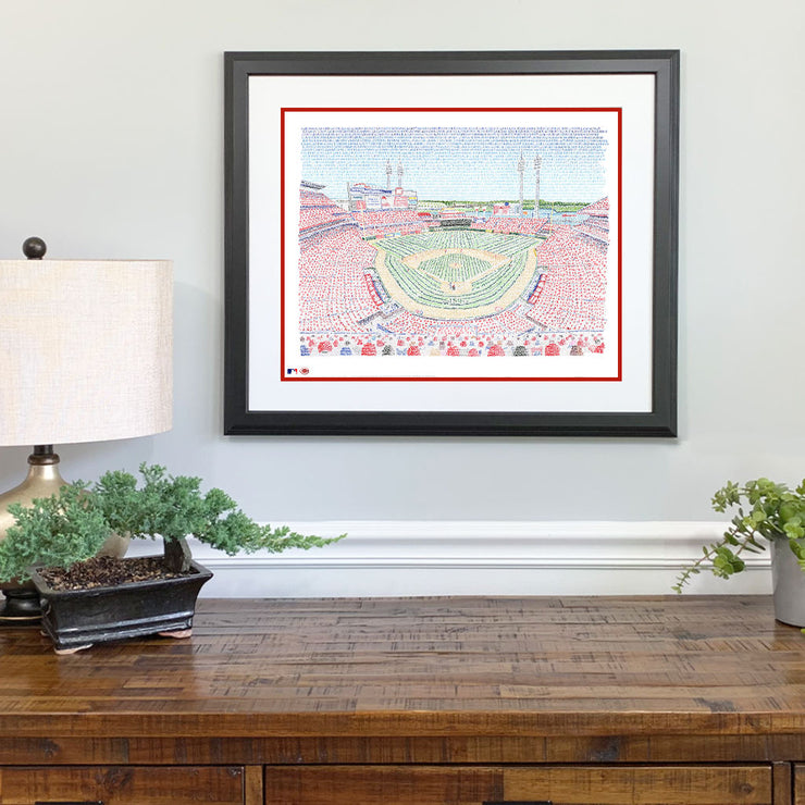 Matted and framed word art print of the Cincinnati Reds’ stadium, one of the best Cincinnati Reds gifts, hangs on wall.