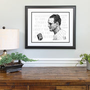 Framed illustrated portrait of Lou Gehrig baseball player for the Yankees made of words on wall above wood desk.