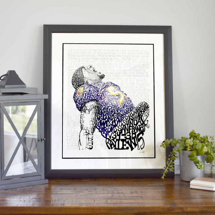 Framed Ray Lewis Ravens football player art made of handwritten words about Ravens on wood dresser next to lantern.