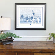 Matted and framed wall word art print depicting 2015 Kansas City Royals World Series win hangs on wall over wooden table.