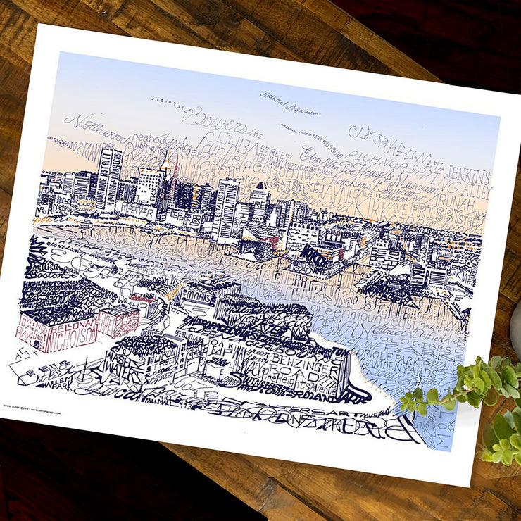 Unframed Baltimore skyline art print, a view formed from handwritten street, and landmark names, lies flat on table.
