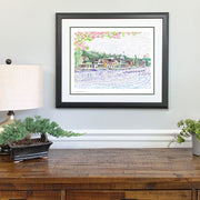 Matted and framed Boathouse Row word art print hangs over wood table.