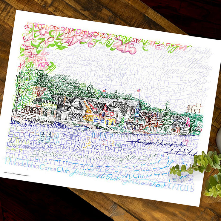  Unframed Boathouse Row artwork print, formed by handwritten names of regattas and nearby places, lies flat on wood table.