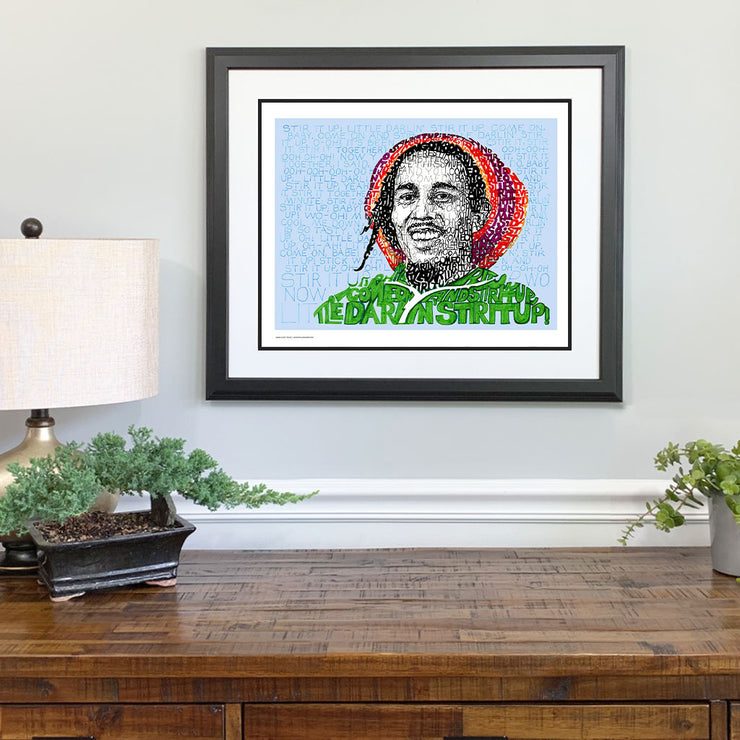 Matted and framed word art portrait of Bob Marley hangs over wooden table, one of the best Bob Marley gifts.
