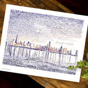 Unframed print of Chicago skyline art, handwritten with names of local places and landmarks, lies flat on wooden table.