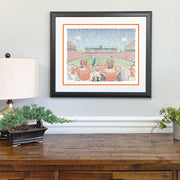 Matted and framed word art print of Clemson Memorial Stadium, one of the best Clemson gifts, hangs on wall over wood table.