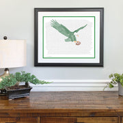 Print of green eagle with brown football made of handwritten words of Philadelphia Eagles rosters above wood dresser.