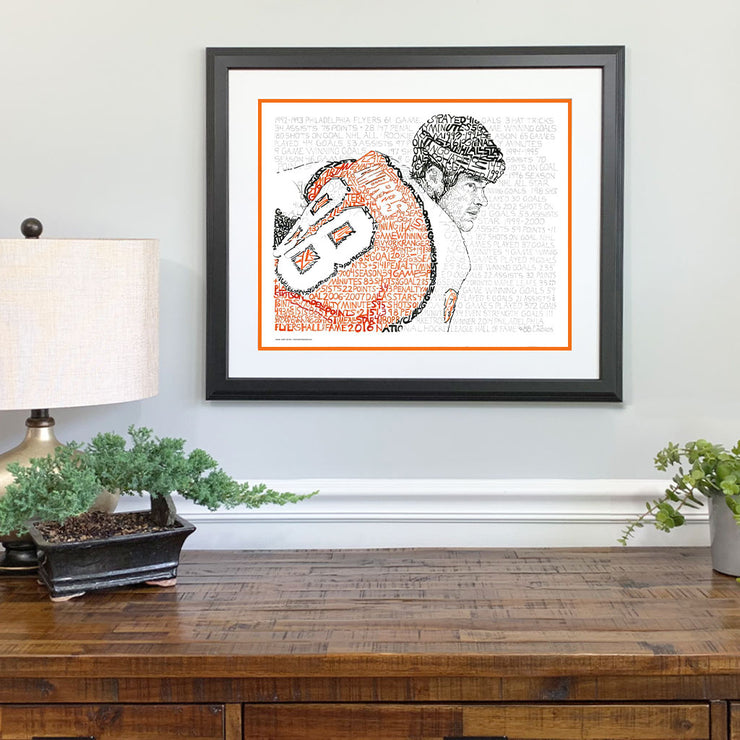 Matted and framed word art portrait of Eric Lindros hangs on wall over wooden table.
