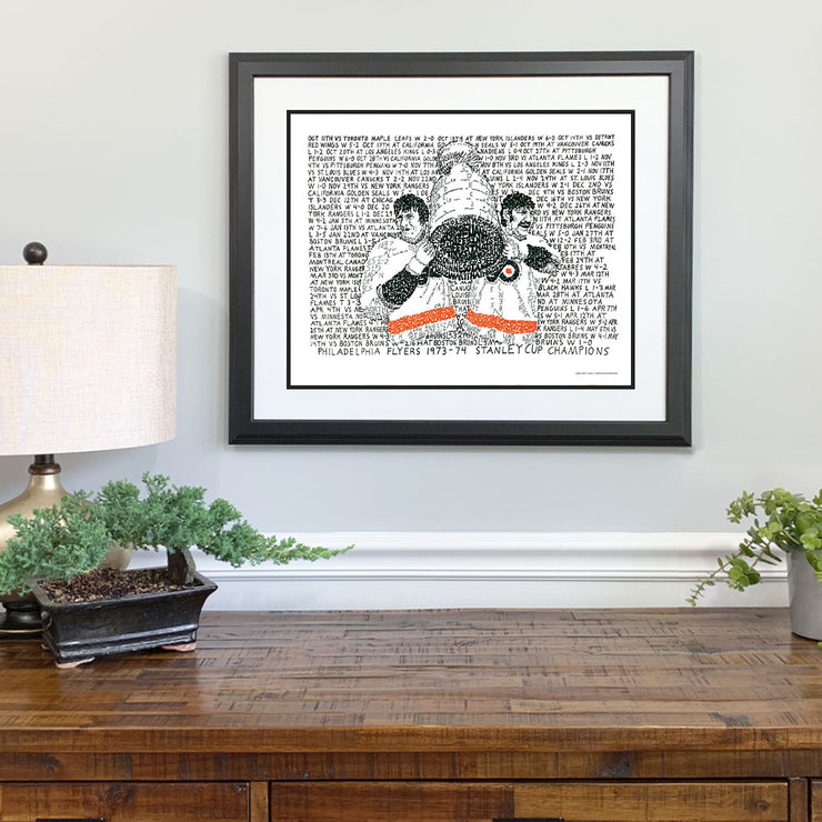 Framed 1973-74 Philadelphia Flyers championship art with Bobby Clarke and Bernie Parent made of handwritten words on wall.