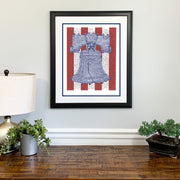 Matted, framed print of Liberty Bell art, handwritten with the text of the Declaration of Independence, hangs on wall.