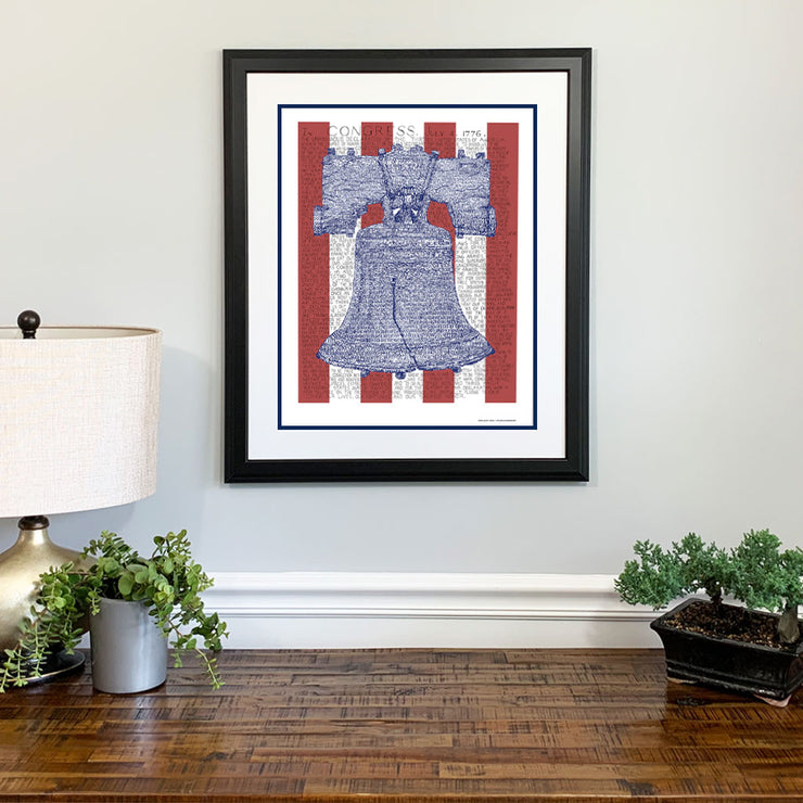 Matted, framed print of Liberty Bell art, handwritten with the text of the Declaration of Independence, hangs on wall.