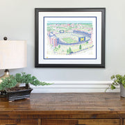 Illustration print of hand-written words depicting ariel view of the big house Michigan Stadium above wood dresser.