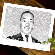 Black and white Martin Luther King Jr. artwork made of hand-written words about the life of Dr. King on wood table.