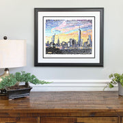 Framed New York art print of city skyline made with multi-colored hand-written words above wood dresser.
