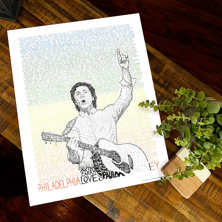 Paul McCartney poster with artist holding guitar in green, yellow, and orange hand-written words of all his Philly concerts.