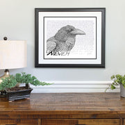 Framed poster of Edgar Allan Poe art of raven in black and white made of handwritten Poe poem “The Raven” above dresser.