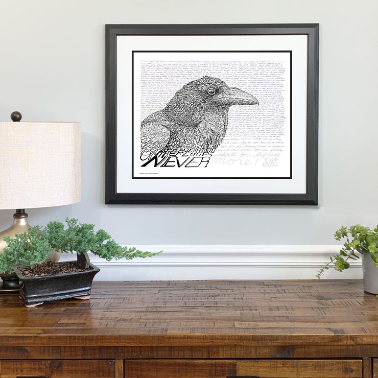 Framed poster of Edgar Allan Poe art of raven in black and white made of handwritten Poe poem “The Raven” above dresser.