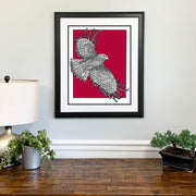 Framed art of St. Joseph Hawk with handwritten phrase "The Hawk Will Never Die" and red background on wall above dresser.