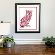 Framed red Owl Temple art of University mascot made of handwritten  words of Temple Fight Song on wall above wood dresser.