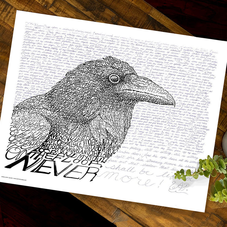Unframed Edgar Allan Poe art of a large raven in black and white made of handwritten Poe poem “The Raven” on wood table.